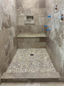 A custom tiled shower with a unique pebble floor design by Carpet Direct Brandon Burley in Muskogee, OK
