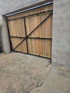 A custom wood and metal frame gate installed in a concrete block wall by Precision Fence in Meridian, MS.
