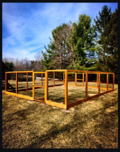 A large custom-built wooden enclosure frame, possibly for animals, installed by Tussing's Fence in Ann Arbor, MI.