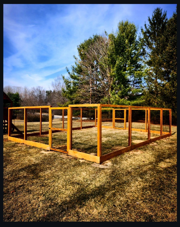 A large custom-built wooden enclosure frame, possibly for animals, installed by Tussing's Fence in Ann Arbor, MI.