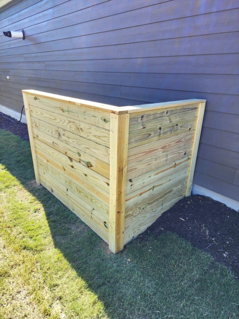 A custom wooden enclosure or utility screen installed next to a house by Endurance Fence Solutions, LLC in Holly Springs, NC