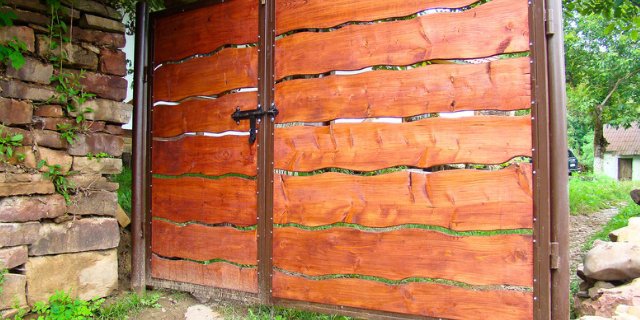 A unique custom wood gate with wavy planks installed by Camp Carlson Fencing in Rochester, NY.