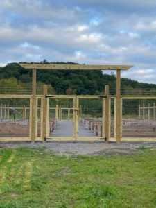 A custom wood gate with wire mesh fencing for a garden or agricultural area by STILL Fencing in Rochester, NY.