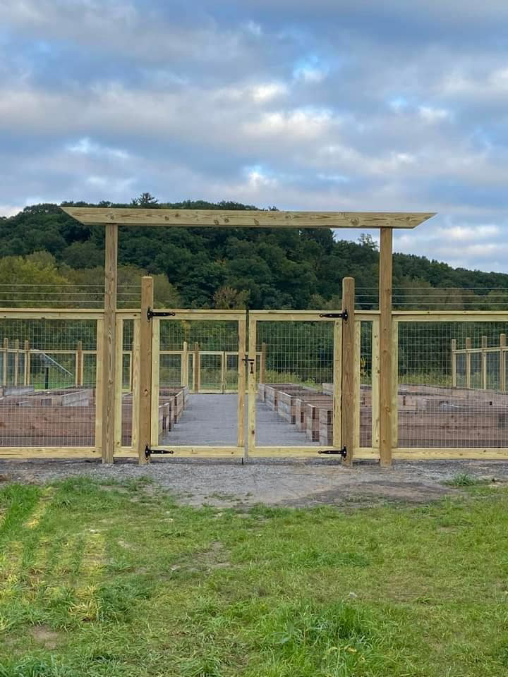 A custom wood gate with wire mesh fencing for a garden or agricultural area by STILL Fencing in Rochester, NY.