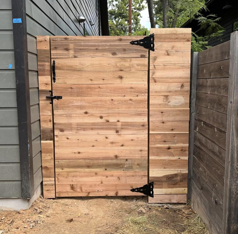 A custom-built wood gate with decorative black hardware installed by K.K. Landscaping & Fencing in Austin, TX.