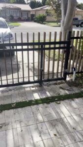 A custom wood and black metal driveway gate with an automatic opener installed by ARE FENCE LLC in Miami, FL.