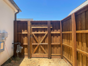 A custom-built wood privacy fence gate installed next to a house by 3M Custom Fence in Lewisville, TX.