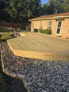 A custom wood and wrought iron driveway gate with stone pillars installed by Ft Worth Fence And Patio in Fort Worth, TX.