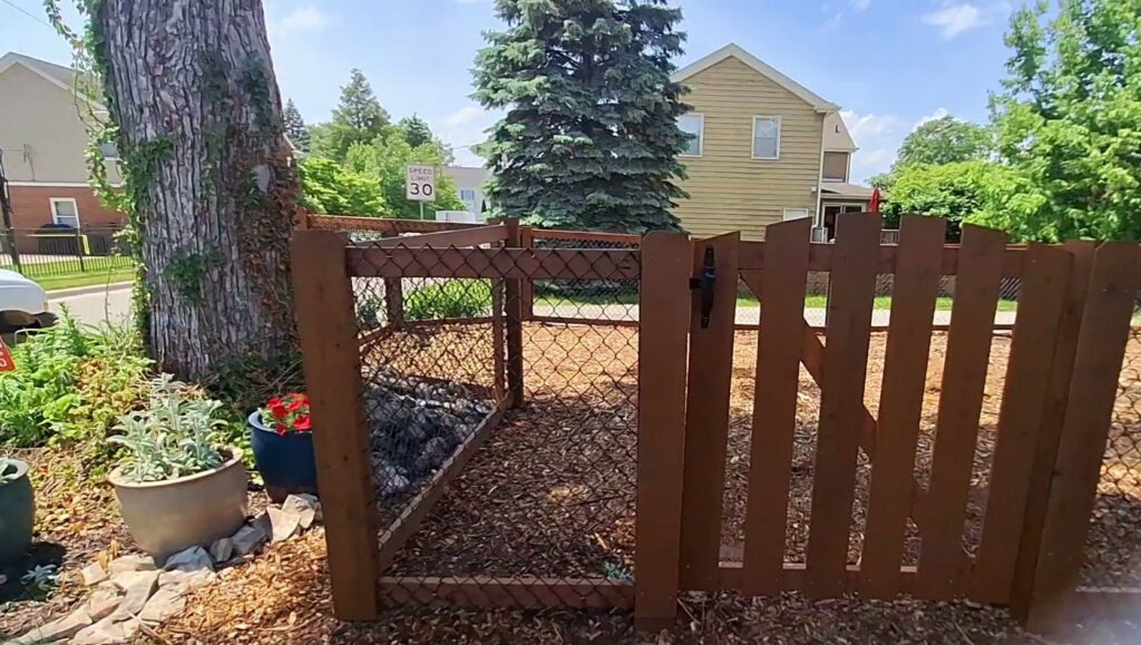 A custom-built wooden enclosure with chain-link mesh and a gate, created by Smith & Company Custom Fence LLC in Niles, MI.