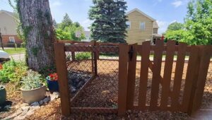 A custom-built wooden enclosure with chain-link mesh and a gate, created by Smith & Company Custom Fence LLC in Niles, MI.