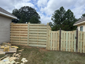 A custom wooden fence with horizontal and vertical slats and a gate by Integrity Construction and Fencing, LLC in Clanton, AL.