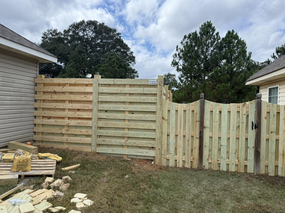 A custom wooden fence with horizontal and vertical slats and a gate by Integrity Construction and Fencing, LLC in Clanton, AL.
