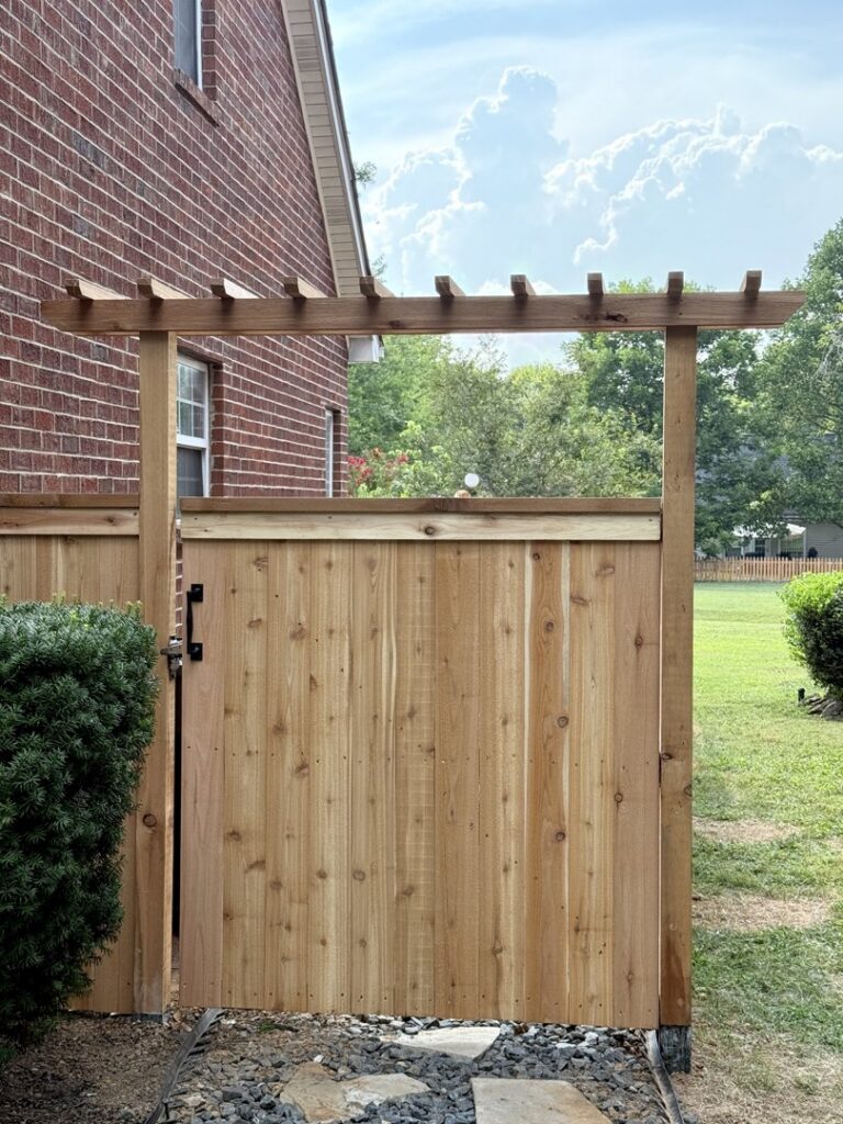 A custom wooden gate with a decorative pergola top installed by Heron Building Co in Franklin, TN.
