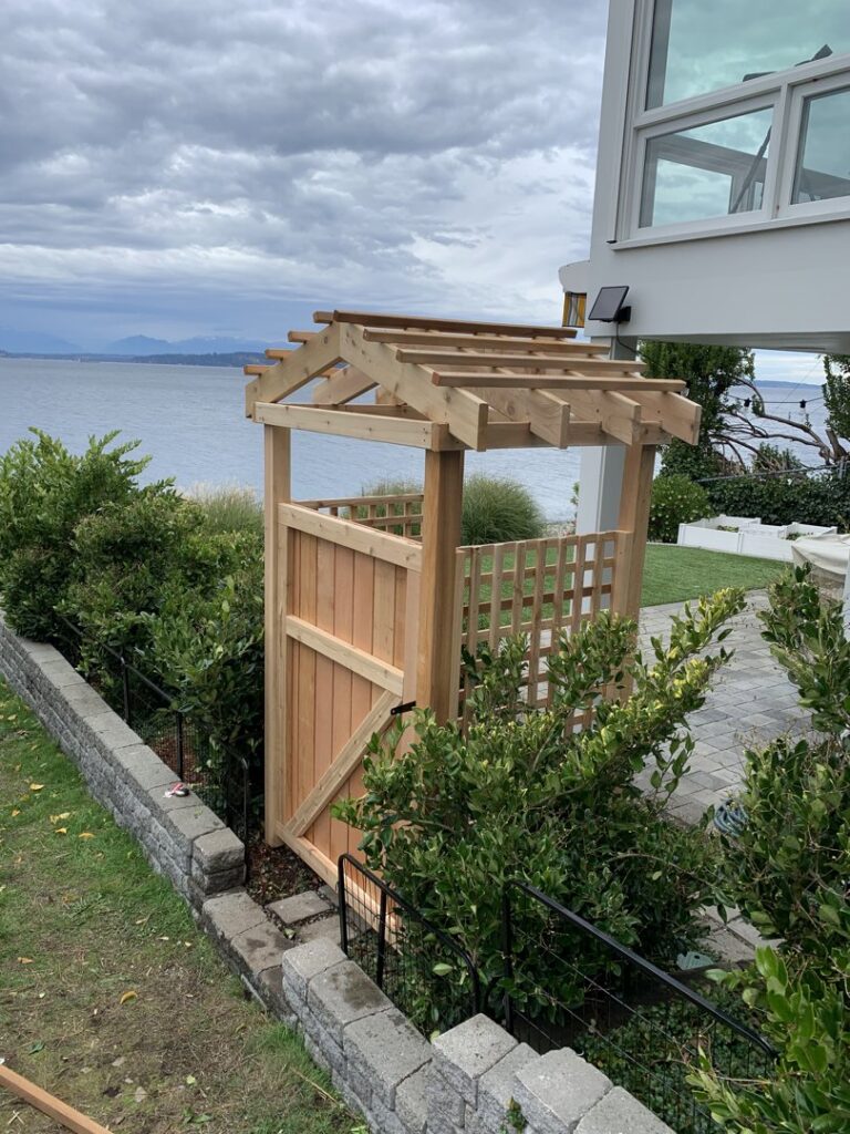 A custom wooden gate with a decorative pergola top overlooking the water by Helmco Fences in Seattle, WA.