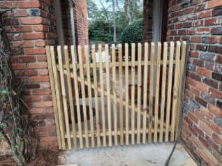 A custom wooden picket gate installed between brick pillars by Almaraz & Sons LLC in Macon, GA.