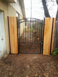 A custom wrought iron gate with decorative wood panels installed by Pro Insulation and Fence in Wichita Falls, TX.