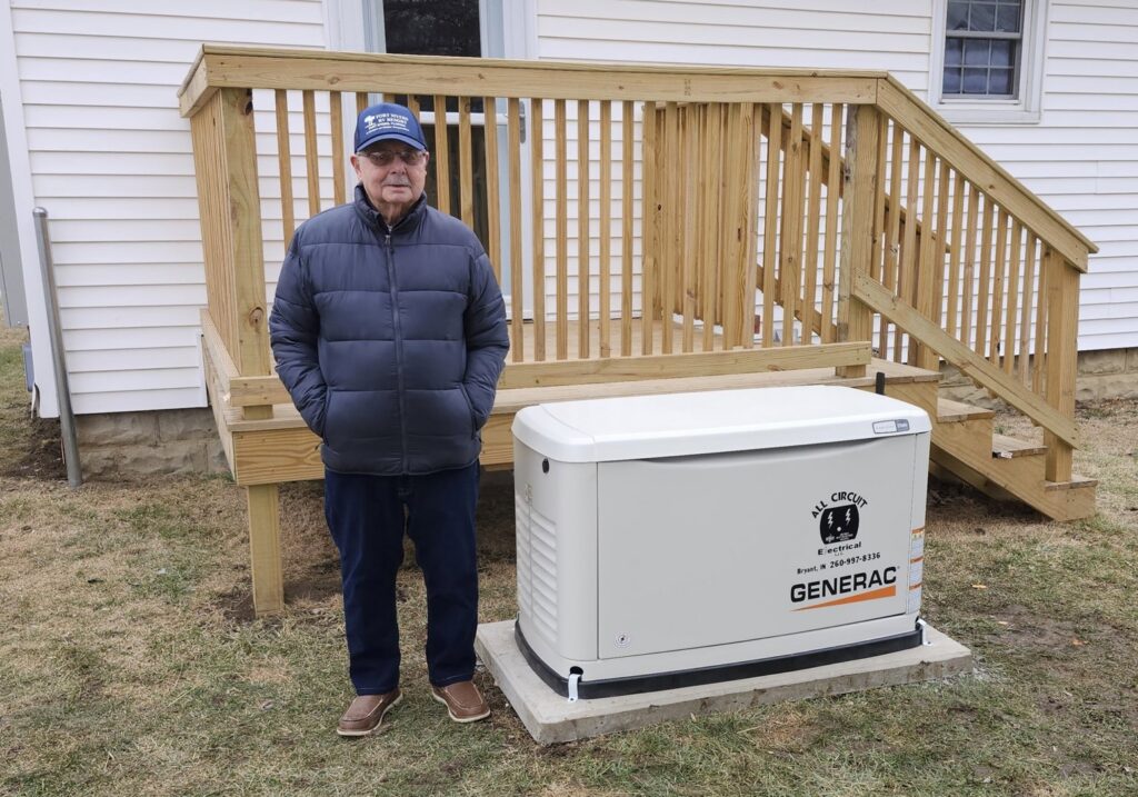A satisfied customer standing next to a newly installed Generac standby generator by All Circuit Electrical LLC in Bryant, IN.