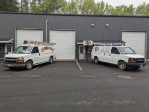 Two branded Daigle Electric service vans with ladders, ready for electrician jobs in Middleboro, MA.