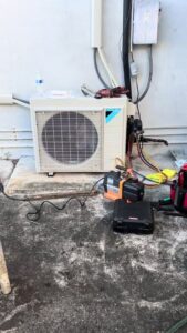 An outdoor Daikin HVAC unit undergoing repair or service with tools and gauges by Ultimate Air Conditioning in Pearl City, HI