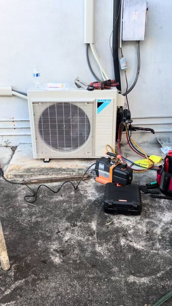 An outdoor Daikin HVAC unit undergoing repair or service with tools and gauges by Ultimate Air Conditioning in Pearl City, HI
