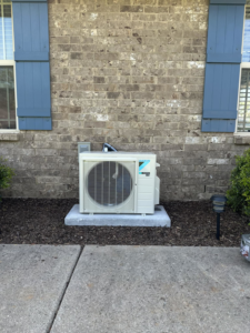 A Daikin mini-split outdoor condenser unit installed next to a brick home by G & N Heating and Cooling in Huntsville, AL.