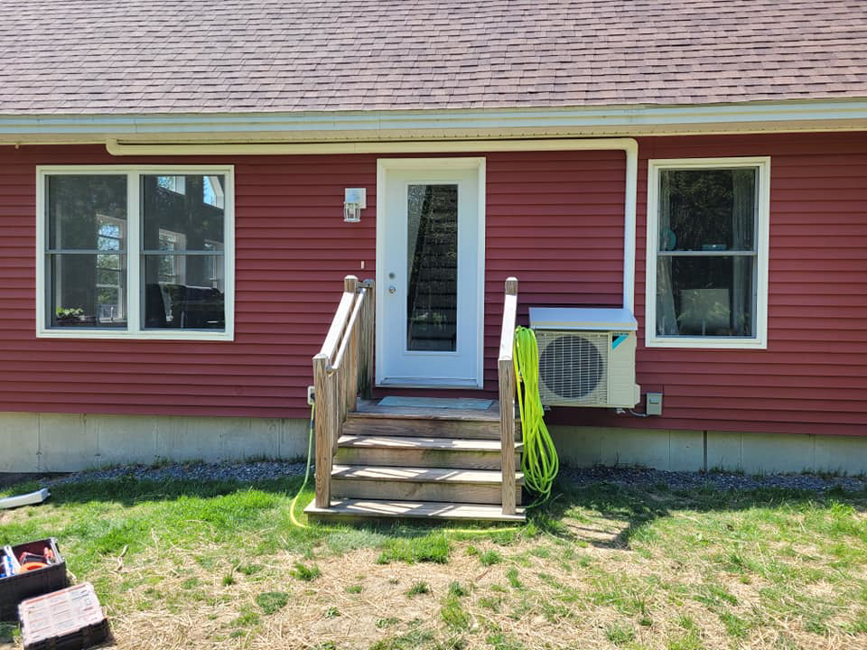 A Daikin mini-split outdoor unit installed on the side of a red house by Maine Thermal Energy Services in Ellsworth, ME
