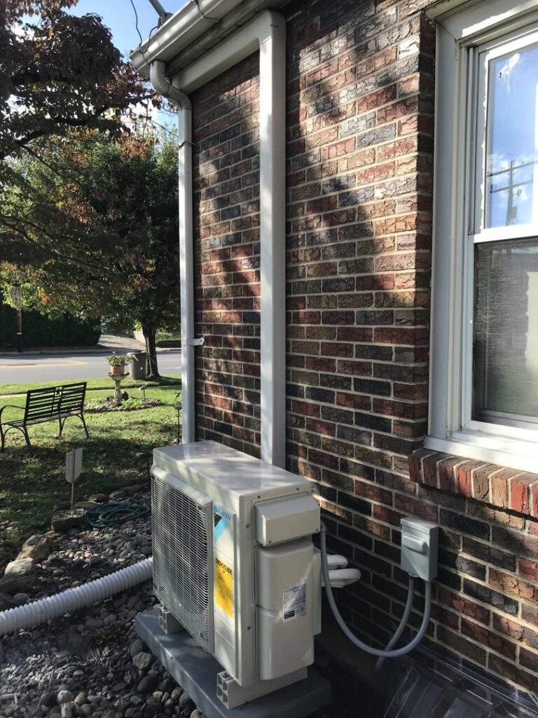 A Daikin mini-split outdoor unit installed on the side of a brick house by Grozier Heating and Air Conditioning, LLC in Allentown, PA.