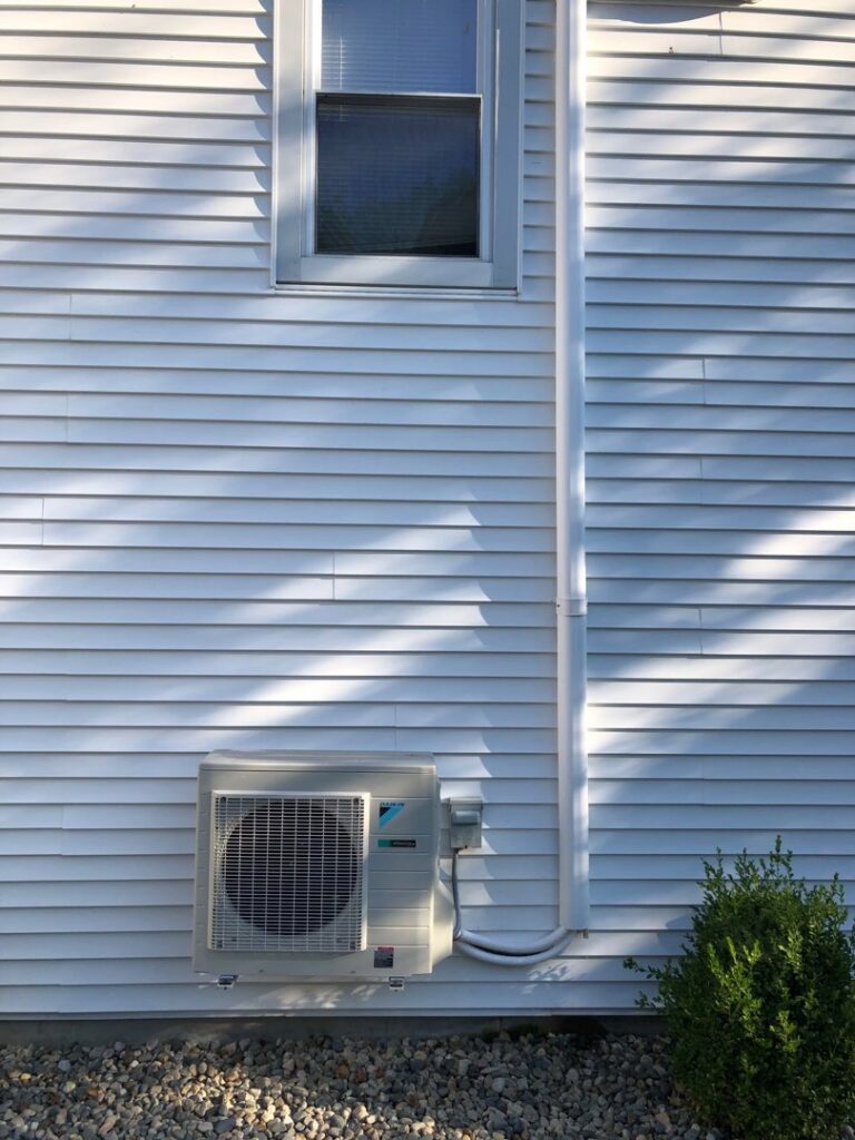 An outdoor Daikin air conditioning unit installed on a home by Derry Plumbing & Heating in Derry, NH.