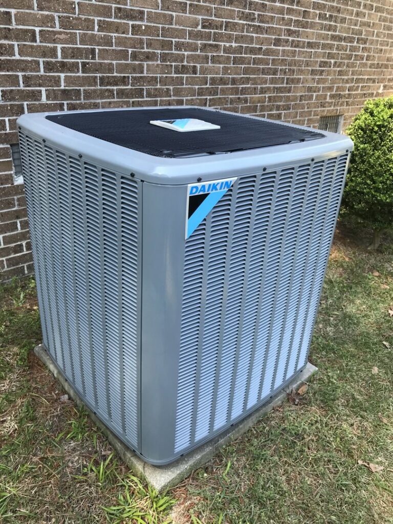 A Daikin outdoor HVAC unit installed next to a brick house by All American Heating and Air in Warner Robins, GA.
