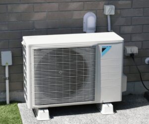 A Daikin outdoor HVAC unit installed next to a brick wall of a building by T & T HVAC in Amherst, OH.