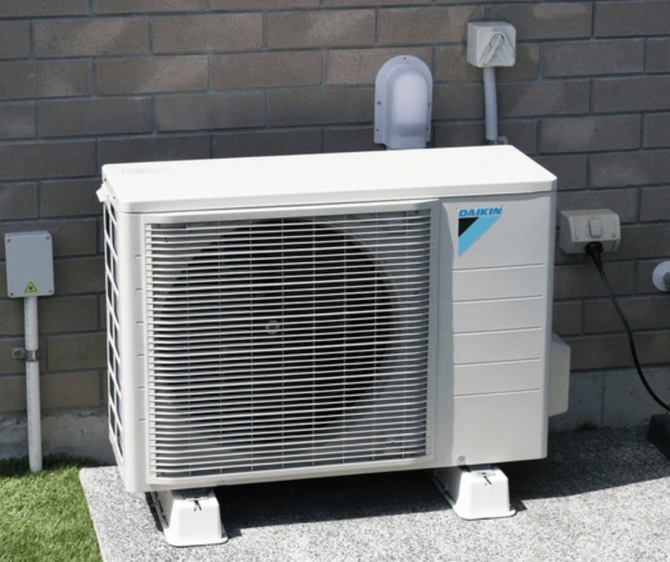 A Daikin outdoor HVAC unit installed next to a brick wall of a building by T & T HVAC in Amherst, OH.