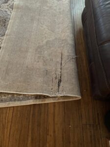 A close-up of a damaged area rug with tears, indicating potential repair or replacement services by Hydro Clean in Baltimore, MD.