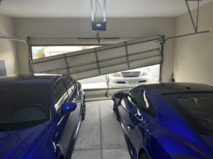 A severely damaged and bent garage door inside a residential garage, indicating a need for repair or replacement by Million Garage Door Services in Colorado Springs, CO.