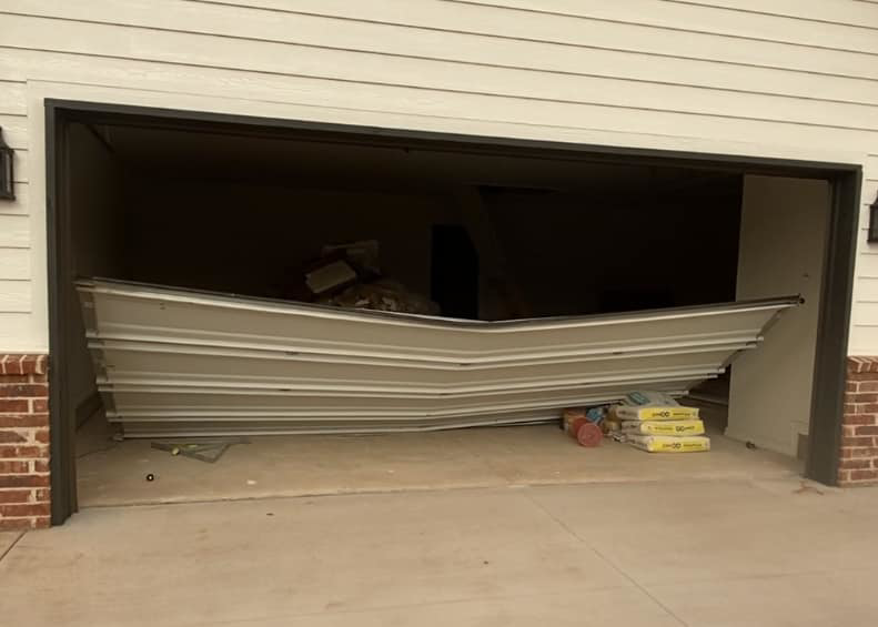 A severely damaged and bent garage door requiring repair or replacement by Unhinged Garage Doors LLC in Oklahoma City, OK.
