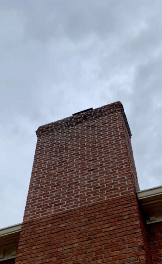 A damaged brick chimney showing wear at the top, indicating need for repair by Professional Fireplaces and Chimney Sweeps in Huntsville, AL.