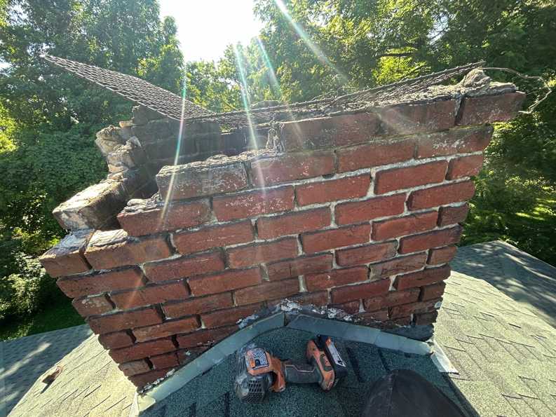 A severely damaged brick chimney on a roof requiring repair, serviced by The Chimney Guys in Jackson, TN.