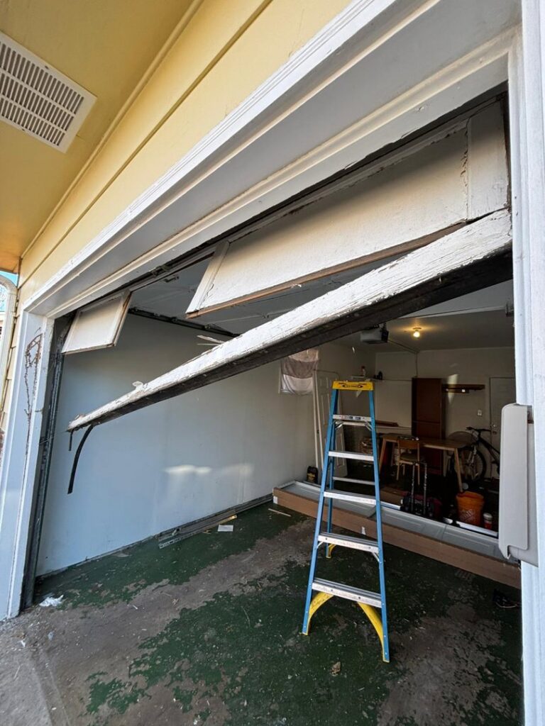 A severely damaged and broken garage door requiring repair or replacement service from Greeley garage door repair in Greeley, CO.