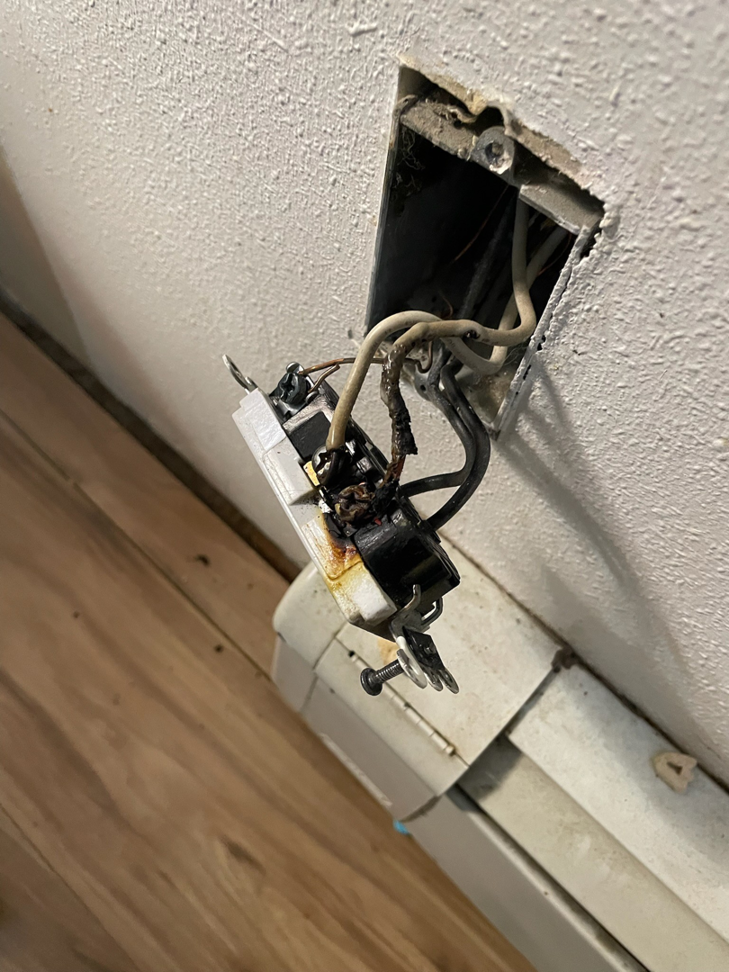 A close-up of a damaged and burnt electrical outlet requiring repair by The Alaskan Electricians in Anchorage, AK.