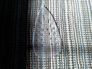 Close-up of a damaged striped carpet, showing the need for repair by Carpet Repair Specialists in Litchfield, NH.