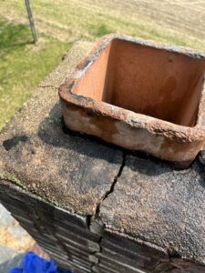 Close-up of a damaged chimney crown and flue tile, showing cracks and wear, by Maximum Energy Savers in Philadelphia, PA