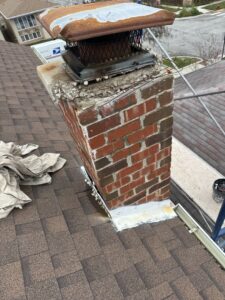 A damaged chimney on a residential roof, showing wear and tear, before repair by Chimney Usa Inc in Chicago, IL.