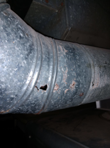 Corroded and damaged metal HVAC ductwork with holes, indicating a need for repair by SM Heating and Cooling in Rochester, NY