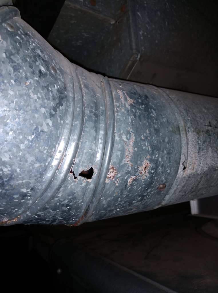 Corroded and damaged metal HVAC ductwork with holes, indicating a need for repair by SM Heating and Cooling in Rochester, NY