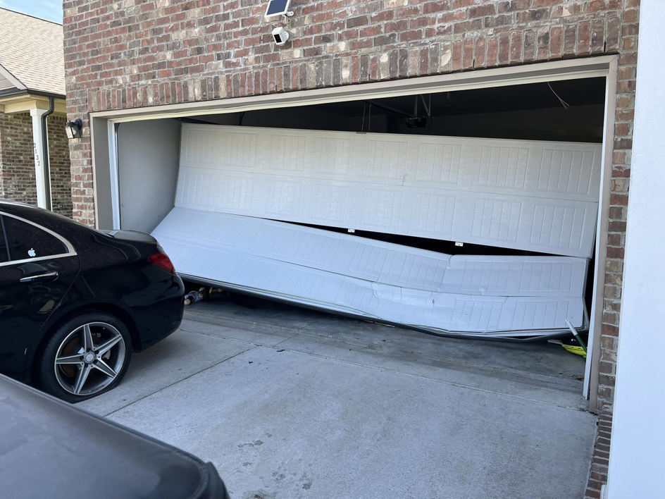 A severely damaged and crumpled white garage door requiring repair or replacement from J&S Garage Door Services in Franklin, TN.