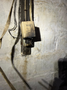 A damaged electrical box with burn marks and exposed wires, showing a repair need by KNK Electric in Pittsburgh, PA.