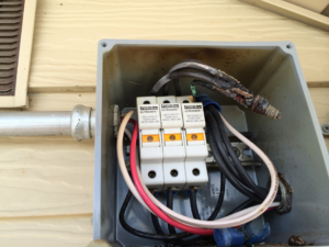 An open electrical fuse box with damaged wiring, showing a repair need by Watts Happening Electric in Lakewood, CO.