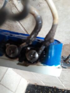 A close-up of a burnt and damaged electrical outlet with discolored wires, requiring urgent repair by Certified Electrician Albuquerque NM.