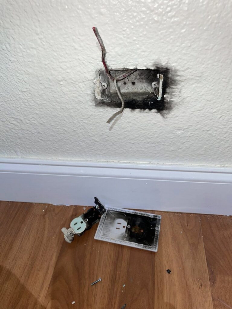 A damaged electrical outlet with exposed wires and burn marks, requiring repair by MG ELECTRIC INC in Lauderhill, FL