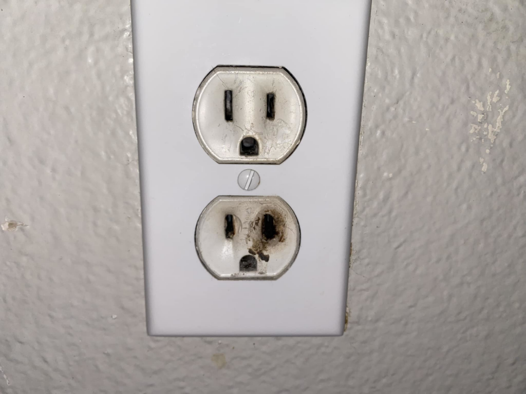 A close-up of a burnt and damaged electrical outlet requiring repair from MLP Services in Sharpsburg, MD