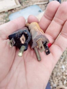 A hand holding two old, damaged electrical plugs, indicating a need for replacement by Johnson Power and Air in Gilbert, AZ.